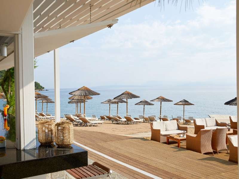 Marbella beach with wicker chairs, sun loungers, straw parasols, and a calm sea view under a cloudy sky.