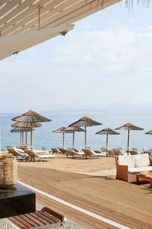 Marbella beach with wicker chairs, sun loungers, straw parasols, and a calm sea view under a cloudy sky.