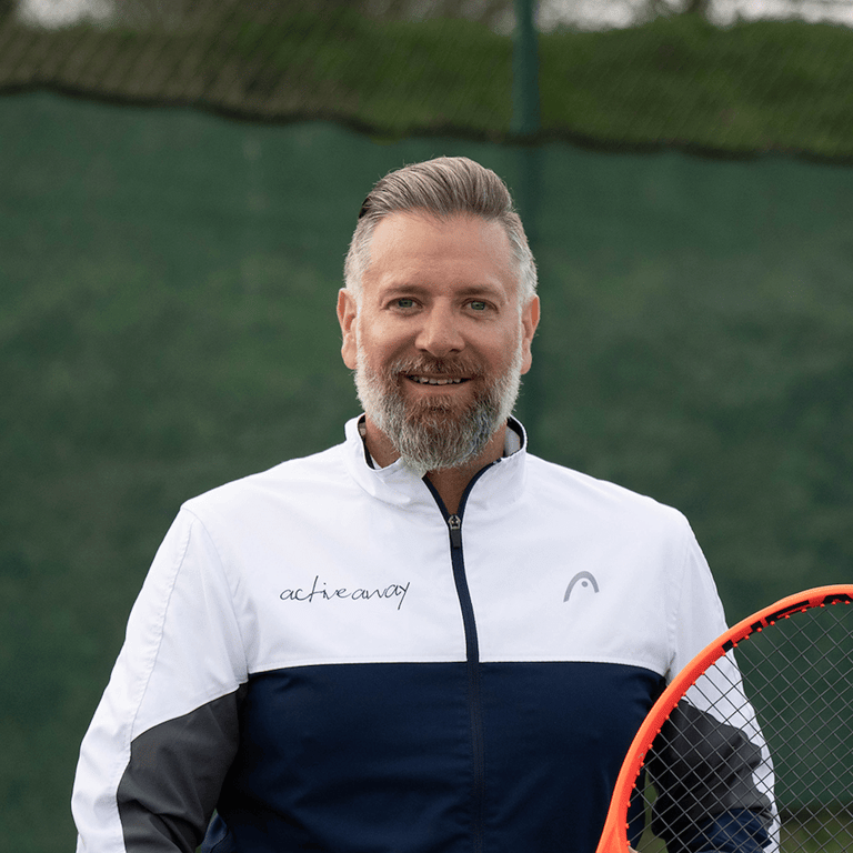Matthew Allen in a white and blue tennis jacket holding a tennis racquet, standing on a tennis court.