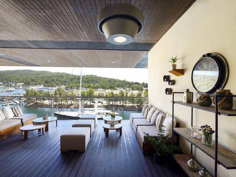 Outdoor deck at Meliton Gallery with lounge furniture, marina view, and green hills in the background.