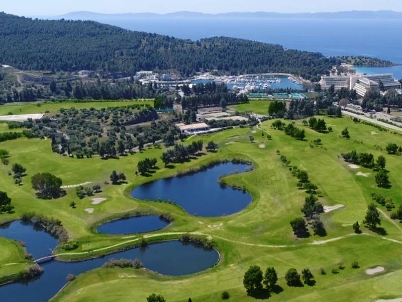 Aerial view of Meliton Gallery at Porto Carras Resort, featuring golf courses, lakes, hotels, and marina with the Aegean Sea in the background.