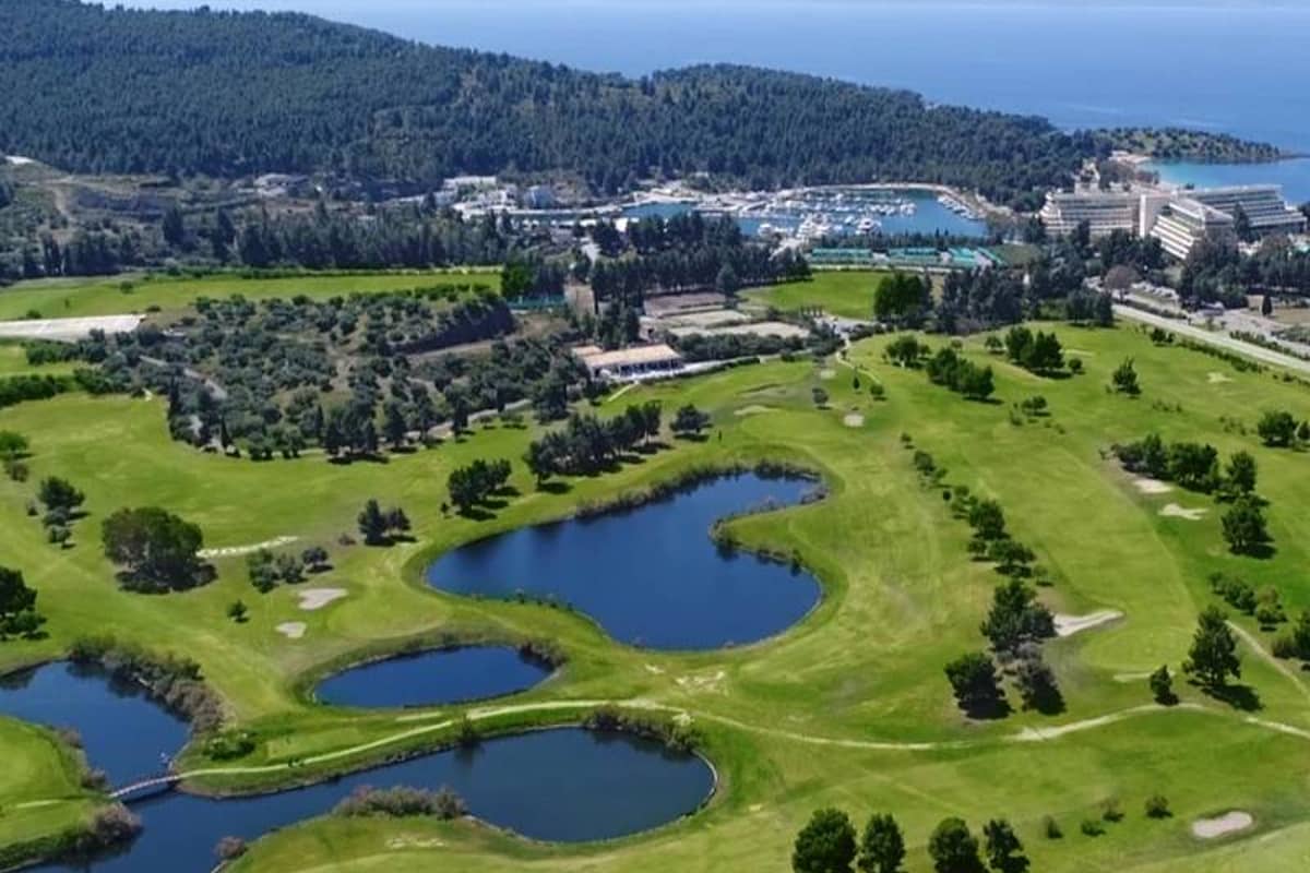 Aerial view of Meliton Gallery at Porto Carras Resort, featuring golf courses, lakes, hotels, and marina with the Aegean Sea in the background.