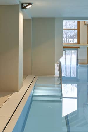 Indoor pool at Mira Alagna Mountain Resort & Spa with wooden accents and mountain view through large windows.