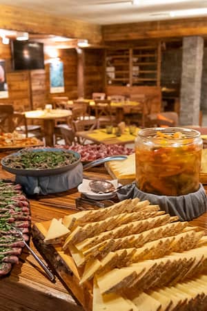 Restaurant at Mira Alagna Mountain Resort & Spa with a spread of meats, cheeses, and preserves, set in a rustic dining room with stone walls.