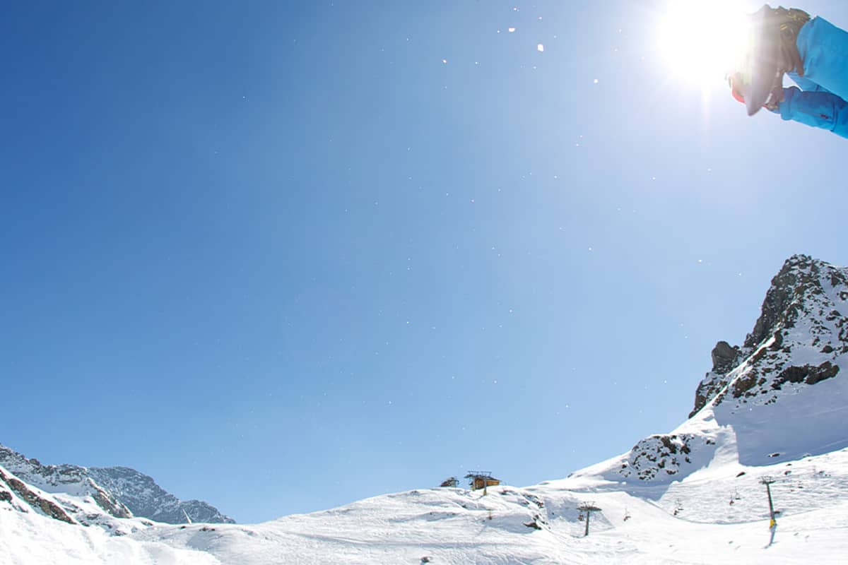 Ski jumper in vibrant blue gear soaring over snow-covered slopes at Mira Alagna Mountain Resort & Spa with mountains in the background.