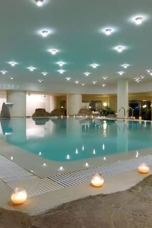 Indoor swimming pool at Oliva Nova Padel with rock formations and candle lighting for a relaxing atmosphere.