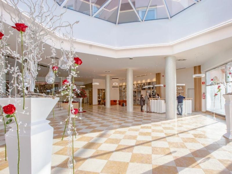 Lobby of Oliva Nova Padel Gallery with elegant floor tiles, modern decor, and floral arrangements with red roses.
