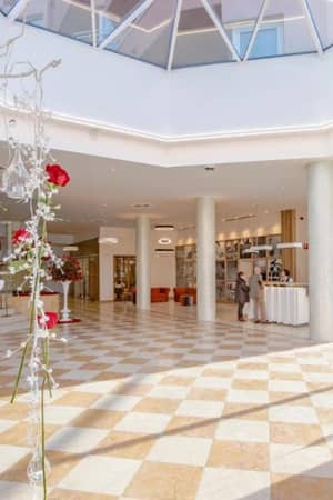 Lobby of Oliva Nova Padel Gallery with elegant floor tiles, modern decor, and floral arrangements with red roses.