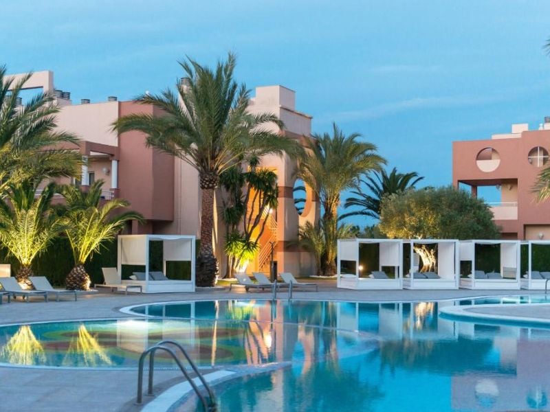 Outdoor pool area at Oliva Nova Resort with modern cabanas and palm trees, offering a relaxing atmosphere.