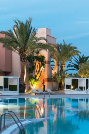 Outdoor pool area at Oliva Nova Resort with modern cabanas and palm trees, offering a relaxing atmosphere.