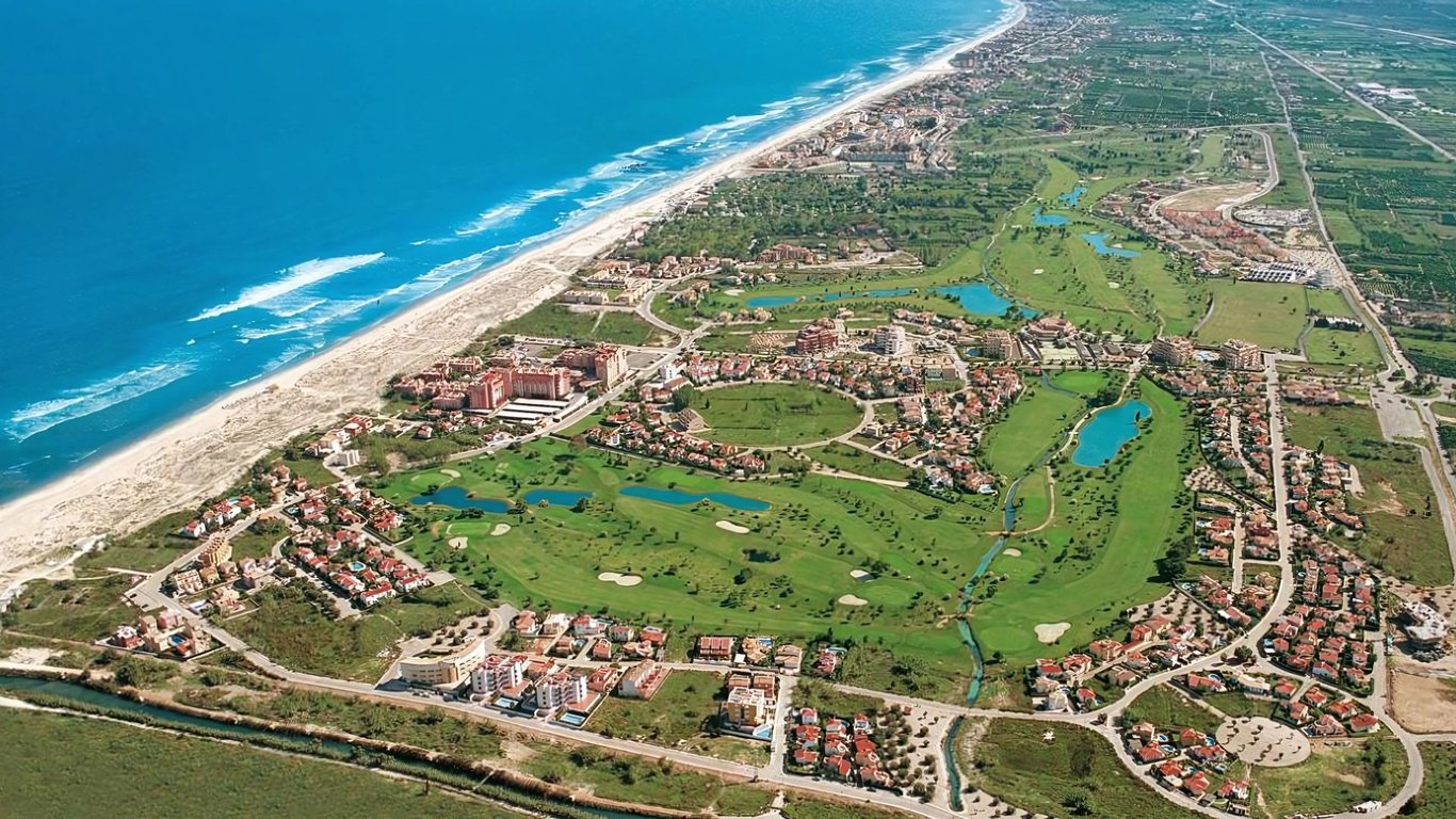Aerial view of Oliva Nova Beach & Golf Resort with golf courses, villas, and the Mediterranean Sea coastline.