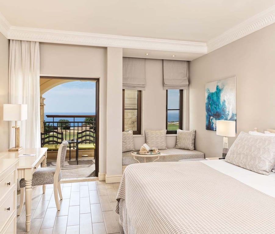 Luxurious one-bedroom suite with a king-size bed, modern decor, balcony with sea view, and elegant furnishings.