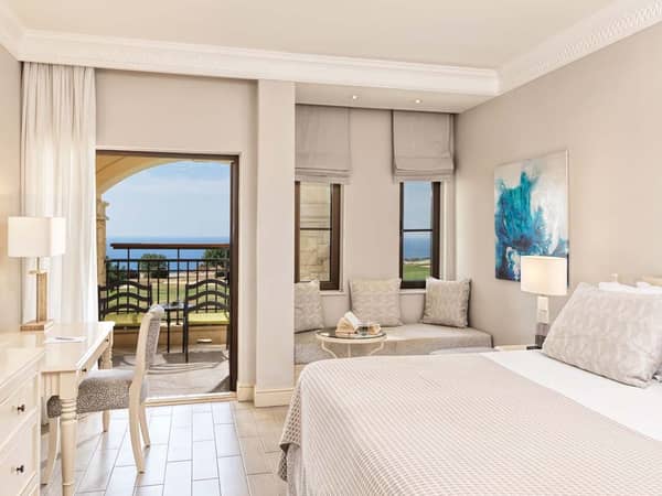 Luxurious one-bedroom suite with a king-size bed, modern decor, balcony with sea view, and elegant furnishings.