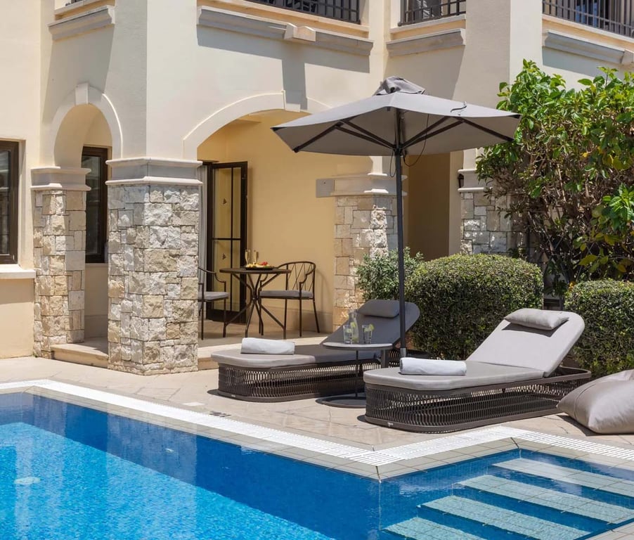 Luxurious one-bedroom suite with a private pool, featuring sun loungers, parasol, and limited sea view.