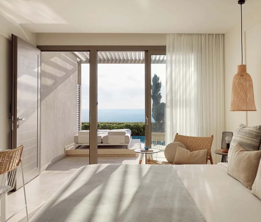 Luxurious one-bedroom suite with swim-up pool access, partial sea view, cosy bed, and glass doors leading to a terrace with a sun lounger.