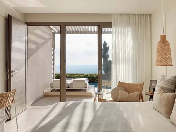 Luxurious one-bedroom suite with swim-up pool access, partial sea view, cosy bed, and glass doors leading to a terrace with a sun lounger.