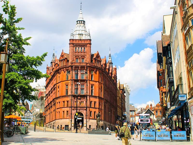 Victorian Gothic Prudential Building in Nottingham city centre with a red-brick facade and bustling street activity.