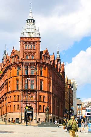Victorian Gothic Prudential Building in Nottingham city centre with a red-brick facade and bustling street activity.