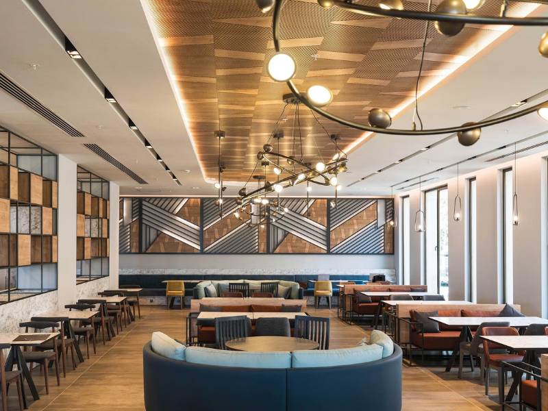 Modern restaurant interior at Paloma Family Holidays, featuring stylish lighting, geometric wall art, and comfortable seating.