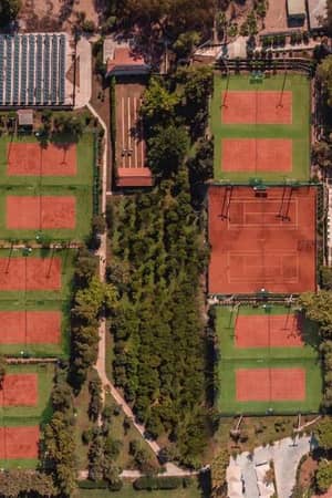 Aerial view of Paloma Gallery showing six clay tennis courts surrounded by trees and greenery.