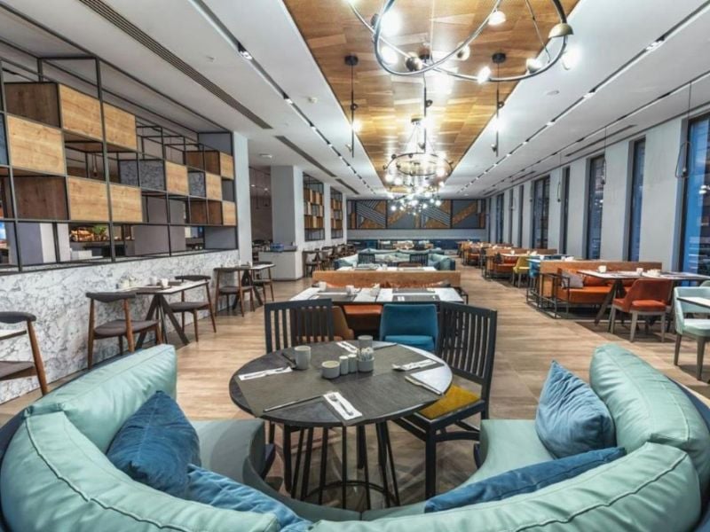 Dining lounge at Paloma Gallery with modern seating, wooden tables, and stylish ceiling lights.