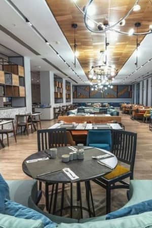 Dining lounge at Paloma Gallery with modern seating, wooden tables, and stylish ceiling lights.