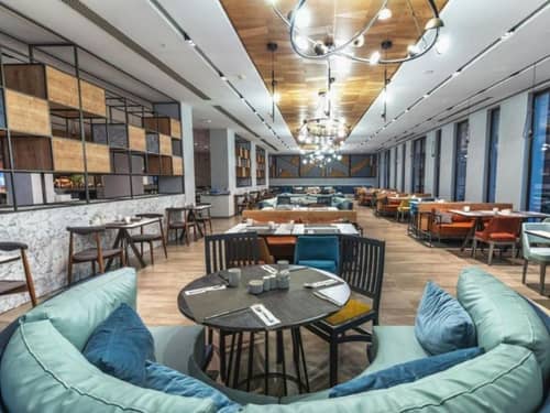 Dining lounge at Paloma Gallery with modern seating, wooden tables, and stylish ceiling lights.