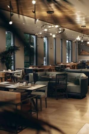 Modern lounge area in Paloma Gallery with wooden tables, sofas, large windows, and hanging lights.