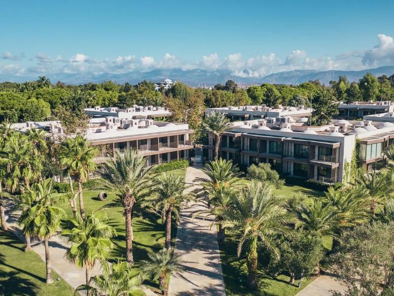 Aerial view of Paloma Gallery luxury apartments with lush greenery, palm trees, and mountains in the background.