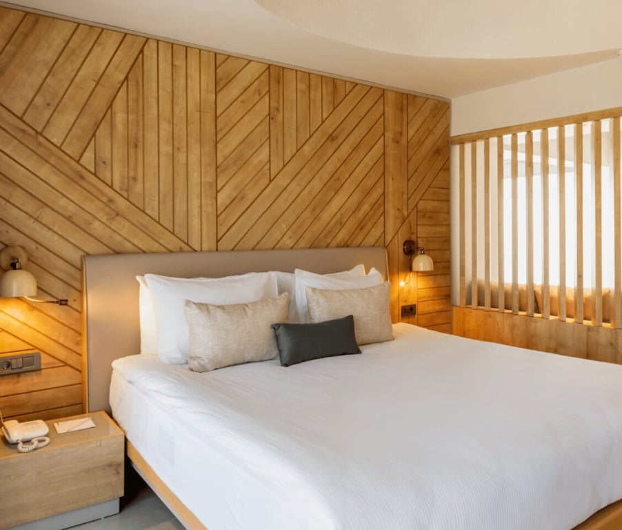 Paloma Orenda Junior Suite featuring a large double bed with white bedding, elegant wood-panelled walls, and ambient lighting.