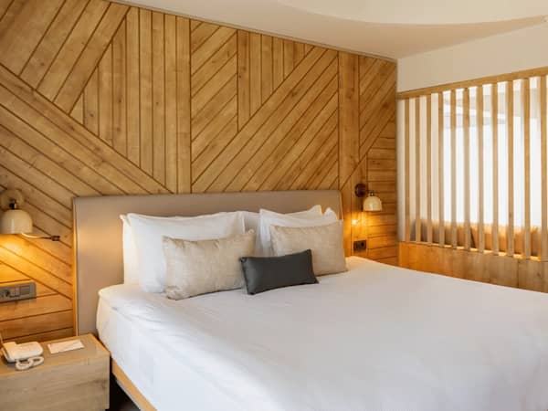 Paloma Orenda Junior Suite featuring a large double bed with white bedding, elegant wood-panelled walls, and ambient lighting.