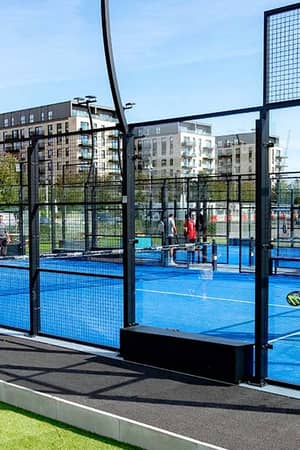 Outdoor padel court at Parkside Padel Clinic with players in action. The setting includes high-rise buildings in the background.