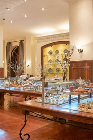 Dining area at Penina Hotel with a buffet of elegant dishes and desserts, warm lighting, and antique-style decor.