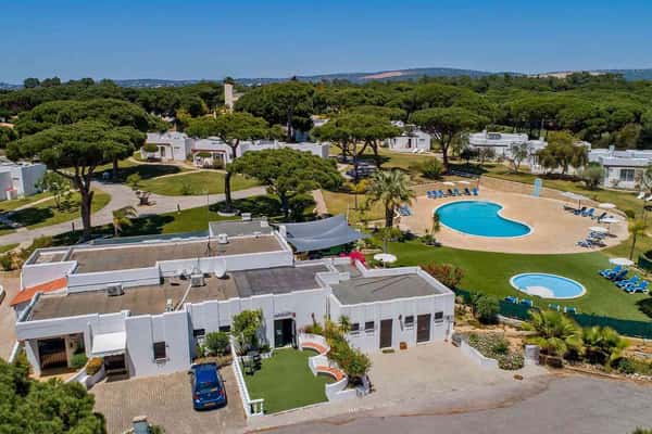 Aerial view of Prado Vilamoura hotel with pools and villas in a lush green landscape on a sunny day.
