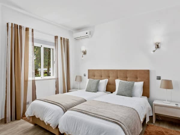 Prado Villas deluxe bedroom with two single beds, modern decor, ambient lighting, and a garden view through a large window.