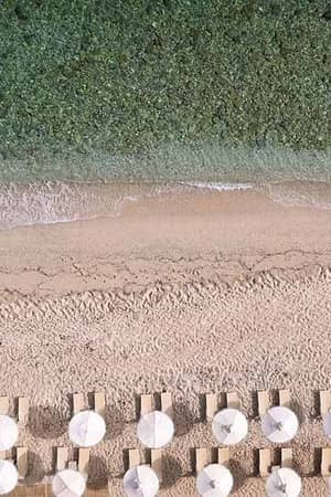 Aerial view of Royal Mare Beach featuring rows of sun loungers and white parasols, next to the turquoise sea.