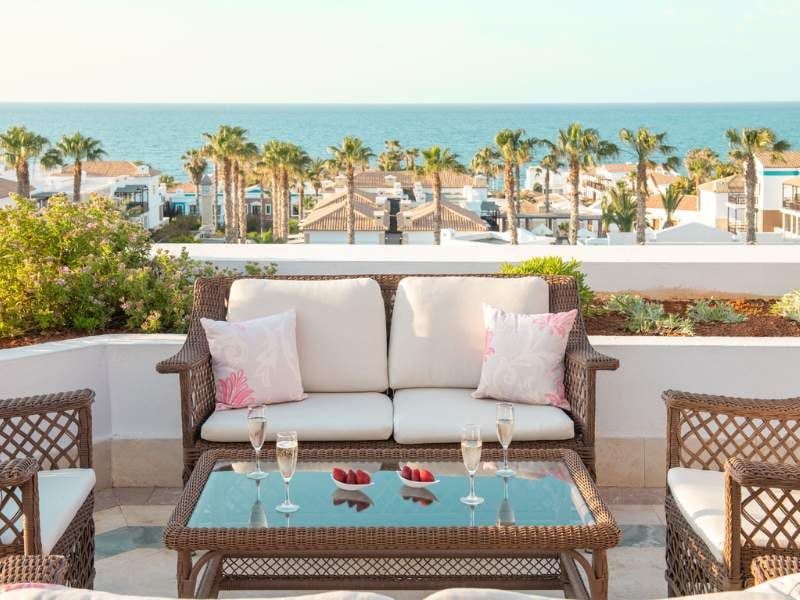 Terrace with wicker furniture, champagne glasses, and view of the sea at Royal Mare Gallery.