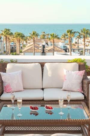 Terrace with wicker furniture, champagne glasses, and view of the sea at Royal Mare Gallery.