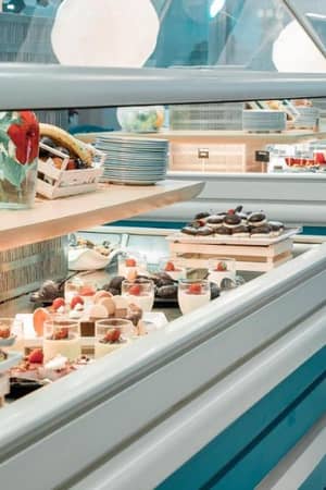 Royal Mare Gallery buffet with fresh fruits in baskets and trays of assorted desserts like pastries and cakes.