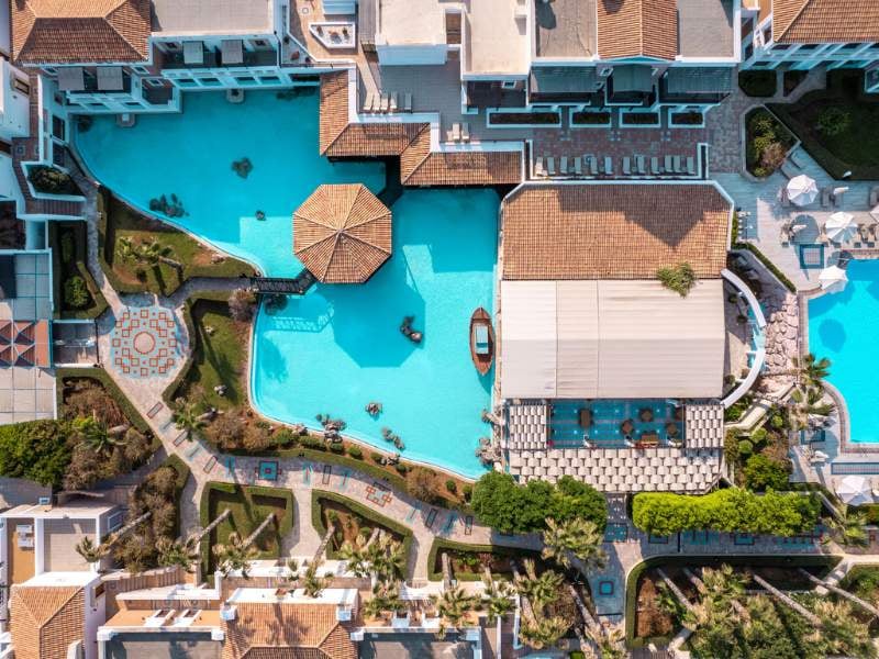 Aerial view of the Royal Mare complex with a large swimming pool, canopied dining area, and landscaped gardens.