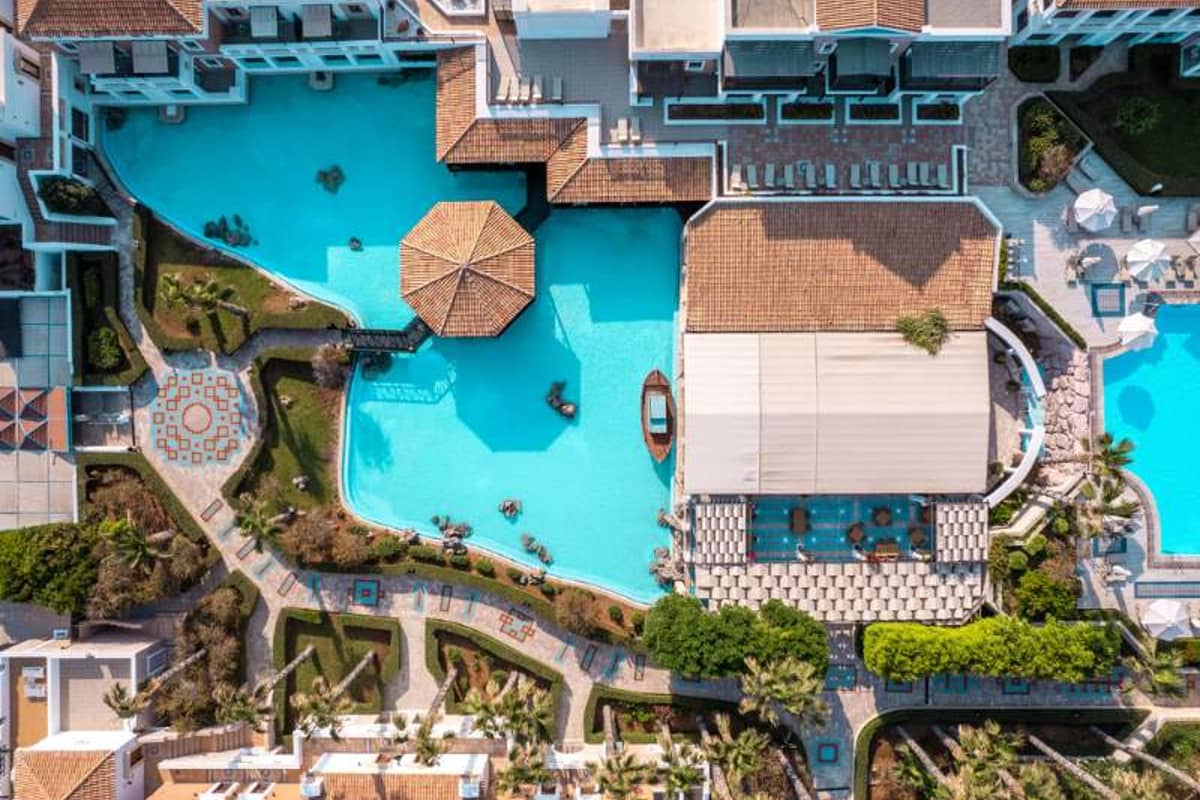 Aerial view of the Royal Mare complex with a large swimming pool, canopied dining area, and landscaped gardens.
