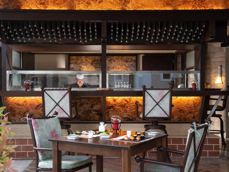 Dining area at Royal Mare Gallery with a table set for fine dining and a view of the kitchen with elegant decor.