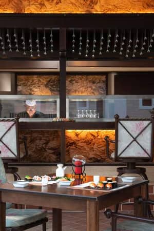 Dining area at Royal Mare Gallery with a table set for fine dining and a view of the kitchen with elegant decor.
