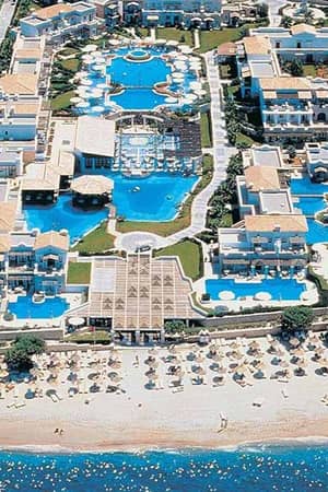 Aerial view of Aldemar Royal Mare resort in Crete, featuring multiple swimming pools, accommodation buildings, and a beachfront with loungers.