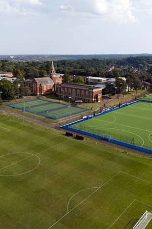 Aerial view of Royal Russell School with football pitches and tennis courts surrounded by greenery.