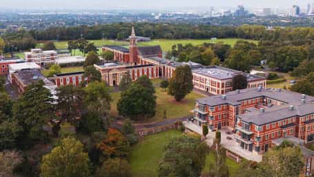 Aerial view of the Royal Russell School campus, featuring brick buildings and abundant greenery on a sunny day.