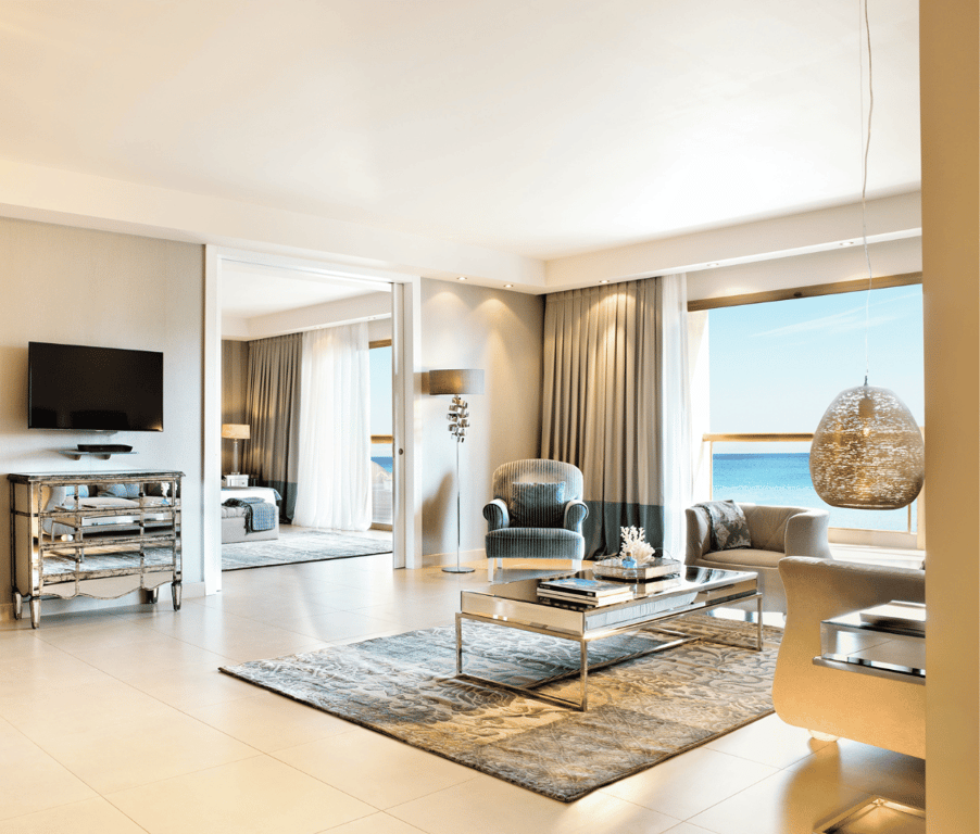 Luxurious two-bedroom family suite at Sani Beach with elegant furnishings and a sea view through large windows.