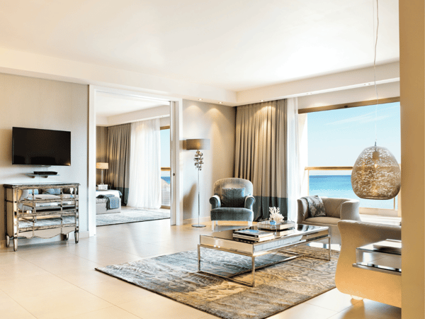 Luxurious two-bedroom family suite at Sani Beach with elegant furnishings and a sea view through large windows.