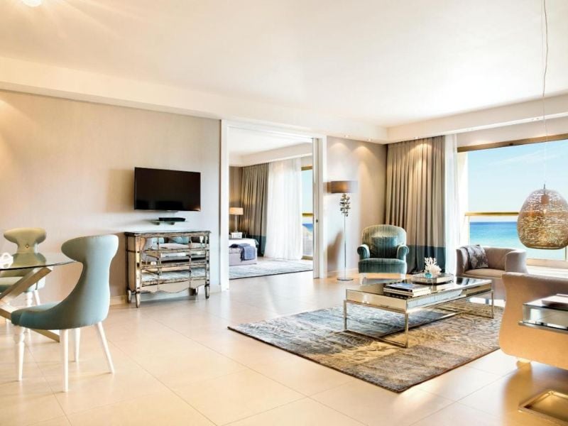 Luxurious hotel room at Sani Beach with modern furniture and large windows showing an ocean view.