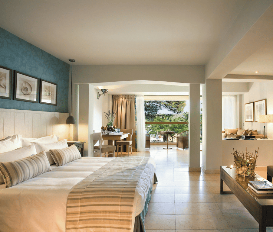 Junior Suite at Sani Beach with a double bed, lounge area, and balcony offering a panoramic sea view.
